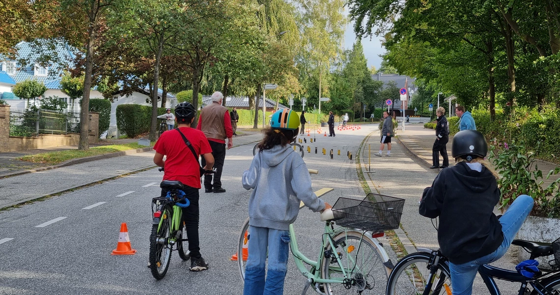 Schulkinder stehen mit ihren Rädern am Start eines Fahrradparcours auf der Straße